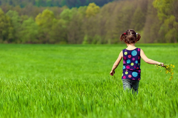 Child Playing in a Green Field